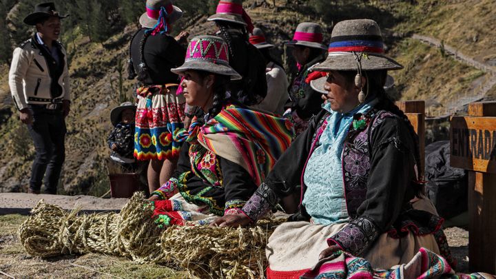 Des femmes tressent des herbes de q'oya pour fabriquer des cordes nécessaires à la fabrication du pont. (CHRISTIAN SIERRA / AFP)