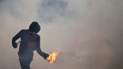 Un manifestant lance un cocktail Molotov sur les policiers anti-émeute, le 20 avril 2017, à Caracas (Venezuela). (CHRISTIAN VERON / X01876)