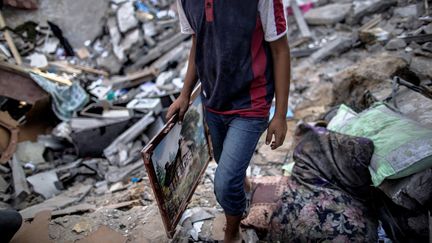 Un jeune Palestinien r&eacute;cup&egrave;re un tableau dans sa maison en ruines, dans le quartier d'al-Shati, le 2 ao&ucirc;t 2014. (MARCO LONGARI / AFP)