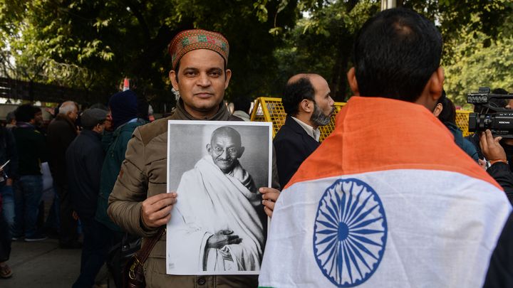 Un manifestant brandit une photo du Mahatma Gandhi lors d'un rassemblement sur le campus de l'université Jawaharlal Nehru, à New Delhi (Inde), le 9 janvier 2020. (SAJJAD HUSSAIN / AFP)