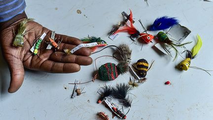 Le secteur des appâts artisanaux "emploie beaucoup de gens", souligne John Nyapola, qui dirige l'entreprise Ojoo Fishing Flies Designers. Dans son atelier près de Nairobi, plumes de flamants roses, poils de lapin, diverses fourrures et tissus parsèment une table. Les commandes personnalisées viennent du Canada, d'Australie ou du Japon. "Woolly Bugger", "Copper John", "Irresistible Adams" et autres noms fantasques se succèdent dans le catalogue de l'atelier qui ne compte pas moins d'un millier de modèles.&nbsp;&nbsp; (LUIS TATO / AFP)