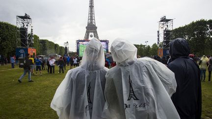 Des supporters sous la pluie, devant l'écran géant du Champs-de-Mars à Paris, pour suivre les matchs de l'Euro, le 12 juin 2016. (GEOFFROY VAN DER HASSELT / AFP)