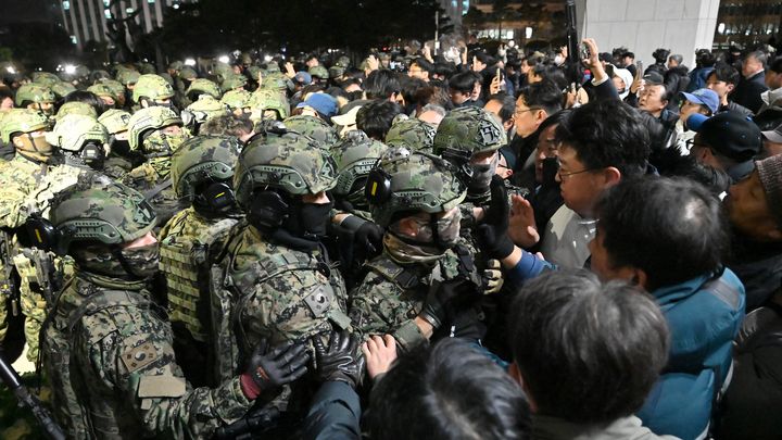 Des militaires tentent d'entrer dans l'Assemblée nationale à Séoul (Corée du Sud), dans la nuit du 3 au 4 décembre 2024. (JUNG YEON-JE / AFP)