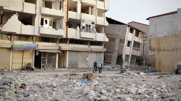 Des habitants discutent au milieu d'immeubles dévastés par les séismes à Samandag (Turquie), le 11 mai 2023. (PIERRE-LOUIS CARON / FRANCEINFO)