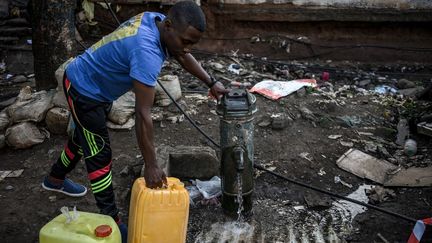 Un homme remplit des bidons d'eau à Koungou (Mayotte), le 23 mai 2023. (PHILIPPE LOPEZ / AFP)