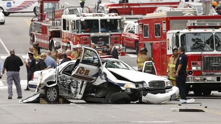 Des pompiers et policiers se pressent autour de la voiture de police accident&eacute;e pendant une course poursuite pr&egrave;s du Capitole &agrave; Washington (Etats-Unis), le 3 octobre 2013. (KEVIN LAMARQUE / REUTERS)