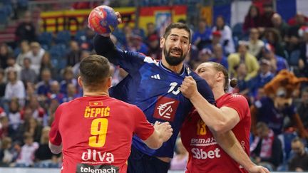 Le Français Nikola Karabatic aux prises avec deux joueurs monténégrins, le 18 janvier 2023, à Cracovie (Pologne). (JANEK SKARZYNSKI / AFP)