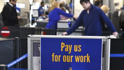 Du personnel de l'aéroport de Philadephie (Etats-Unis) ont posé cette pancarte, "payez-nous pour notre travail", le 25 janvier 2019. (MARK MAKELA / GETTY IMAGES NORTH AMERICA / AFP)