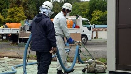 Travailleurs  nettoyant une surface lors d'une opération de décontamination à Naraha, ville située dans la zone d'exclusion de 20 km autour de la centrale japonaise de Fukushima (AFP PHOTO / TOSHIFUMI KITAMURA)