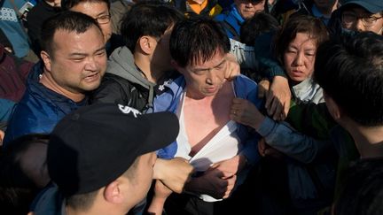 Des proches de victimes du naufrage du "Sewol", en Cor&eacute;e du Sud, molestent&nbsp;un responsable des garde-c&ocirc;tes, le 24 avril 2014, &agrave; Jindo. (ED JONES / AFP)