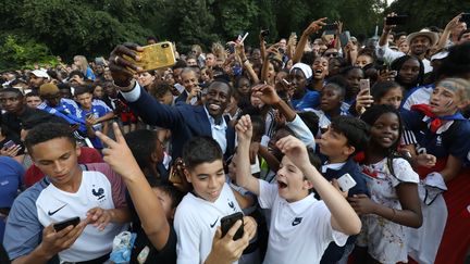 Des jeunes autour du défenseur Benjamin Mendy, lors de la réception des joueurs de l'équipe de France à l'Elysée, à Paris, le 16 juillet 2018. (LUDOVIC MARIN / POOL)