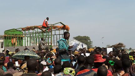 appelle par leurs noms des réfugiés fuyant la violence en RDC, afin de monter dans un bus. Ils seront amenés sur les parcelles de terre qui leur ont été attribuées, où ils pourront construire leurs propres maisons et cultiver.
 (Michele Sibiloni/UNHCR)