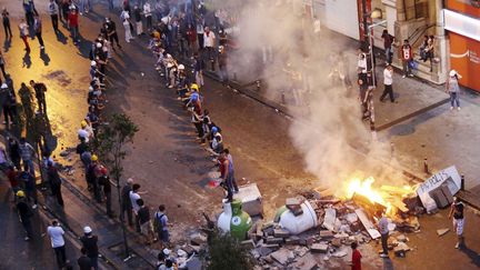 Des manifestants font une cha&icirc;ne pour se passer des pierres lors d'affrontements avec la police &agrave; Istanbul (Turquie), le 16 juin 2013. (REUTERS)