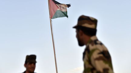 Des soldats du Front Polisario se tiennent, le 17 octobre 2017, près d'un drapeau de la République arabe sahraouie démocratique (RASD) dans le camp de réfugiés de Boujdour, à proximité de de la ville de Tindouf, dans l'ouest de Algérie.  (RYAD KRAMDI / AFP)