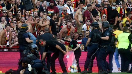 Des policiers anti-émeutes arrêtent un homme après que des supporters de Lens ont envahi le terrain pendant le match de football de L1 français entre le RC Lens (RCL) et Lille (LOSC) au Stade Bollaert-Delelis à Lens, dans le nord de la France, le 18 septembre 2021. (FRANCOIS LO PRESTI / AFP)