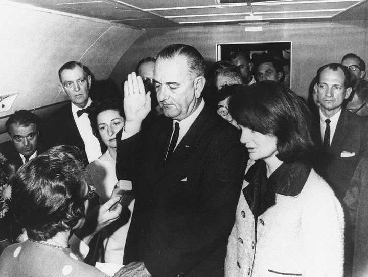 A côté de Jackie Kennedy (à droite), le vice-président américain Lyndon Johnson prête serment dans Air Force One, le 22 novembre 1963, 98 minutes après l'assassinat du président John F.Kennedy à Dallas. (CECIL STOUGHTON-WH PHOTOGRAPHS / JFK PRESIDENTIAL LIBRARY / AFP)