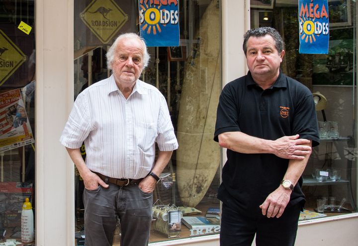 Maurice Lang (à gauche) devant la boutique vintage Swing, ouverte par son fils Philippe Lang (à droite) en face d'Au Gaspillage, la boutique de prêt-à-porter féminin tenue pendant des années par la famille, au cœur de Villeneuve-sur-Lot.&nbsp; (JULIETTE CAMPION / FRANCEINFO)