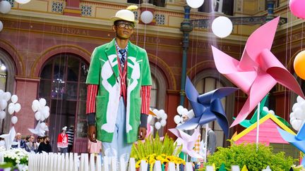 Un show Thom Browne, c'est toujours une mise en scène ! Cette saison, le créateur américain s'est installé dans un jardin de jeux pour enfants. Petites barrières blanches, ballons, moulins à vents de couleurs... le décor est planté. Le show débute avec l'arrivée de mannequins habillés en nains de jardin chargés d'une brouette ou d'une tondeuse à gazon, puis voici des mannequins vêtus de grands manteaux ou de vestes amples (rose, vert, jaune, bleu ou vichy) avec des gigantesques broderies crabes, baleines et homards. En dessous des pantalons, des jupes longues, des shorts au choix et un petit canotier en paille sur la tête !
 (Swan Gallet/WWD/Shutter/SIPA)