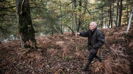 Un témoin fait un geste en désignant l'endroit où il a trouvé le corps du ministre français Robert Boulin il y a 40 ans lors d'une reconstitution de la découverte de son corps, à l'étang Rompu à Saint-Léger-en-Yvelines (Yvelines), le 28 octobre 2019. (MARTIN BUREAU / AFP)