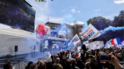 Des policiers brandissent des drapeaux de syndicats de police et allument des bombes fumigènes alors qu'ils se rassemblent devant l'Assemblée nationale à Paris, le 19 mai 2021. (THOMAS COEX / AFP)