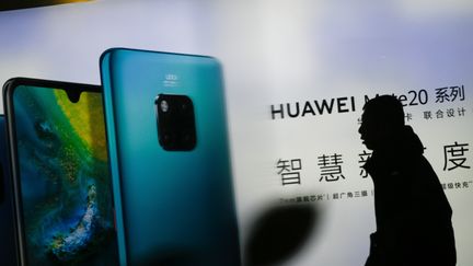 Un homme marche devant une publicité Huawei&nbsp;à Pékin (Chine) le 29 janvier 2019. (WANG ZHAO / AFP)