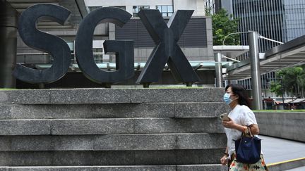 Une femme masquée passe devant la bourse de Singapour, le 7 avril 2020. (ROSLAN RAHMAN / AFP)