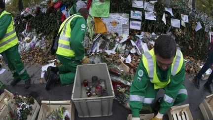 Des hommes sont chargés de ramasser et classer les témoignages et autres hommages aux victimes du 13 novembre déposés sur les différents sites des attentats. 
 (JOEL SAGET / AFP)