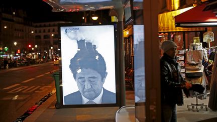 Une affiche détournant une photo du Premier ministre japonais, Shinzo Abe, postée par le collectif Brandalism à Paris, le 28 novembre 2015. (BENOIT TESSIER / REUTERS)