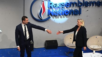 Le président du RN, Jordan Bardella, tend la main à sa prédécesseure, Marine Le Pen, lors d'un congrès du parti, le 5 novembre 2022, à Paris. (ALAIN JOCARD / AFP)