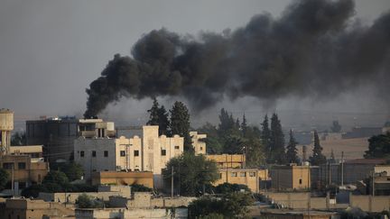 Une colonne de fumée s'échappe de la ville syrienne de Tel Abyad, photographiée le 13 octobre 2019 depuis la localité turque d'Akcakale. (STOYAN NENOV / REUTERS)