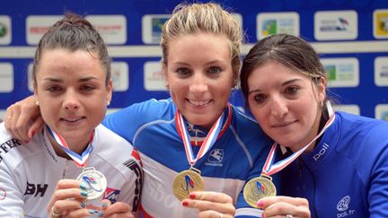 Pauline Ferrand Prevot (C) montre sa médaille sur le podium entourée de la seconde Audrey Cordon (G) et la troisième Medlodie Lesueur (D) (DAMIEN MEYER / AFP)