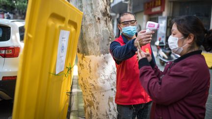 Un membre de "l'équipe d'urgence de Wuhan" prend la température d'une habitante à Wuhan (Chine), le 25 avril 2020.&nbsp; (MAXPPP)