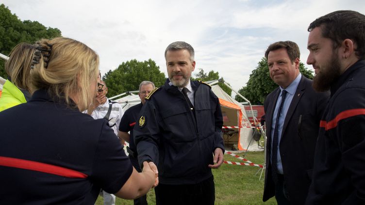 The prefect of Indre, Stéphane Bredin, shakes hands with the firefighters during the teknival organized on May 18, 2023 in Villegongis, despite the ban from the prefecture.  (GUILLAUME SOUVANT / AFP)