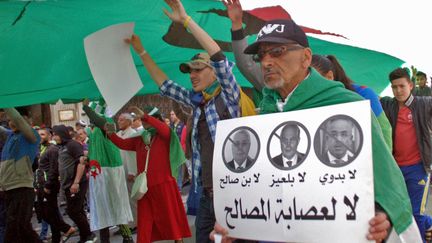 Un manifestant défile contre les "3B" (le&nbsp;président intérimaire Abdelakder Bensalah, le chef du conseil constitutionnel Tayeb Belaiz et le Premier ministre Noureddine Bedoui) lors d'une manifestation à Oran, le 9 avril 2019. Sur la banderolle on peut lire "Non aux voyous". (/ AFP)