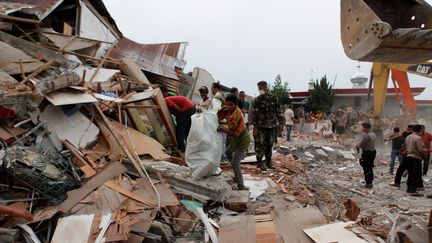 Des habitants marchent dans les décombres d'habitations après un violent séisme à Aceh, en Indonésie, le 7 décembre 2016. (JUNAIDI HANAFIAH / ANADOLU AGENCY / AFP)