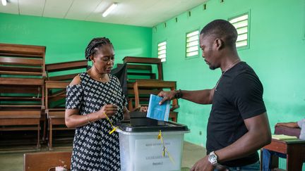 Un électeur dépose son bulletin dans un bureau de vote lors du référendum au Gabon, à Libreville, le 16 novembre 2024. (NAO MUKADI / AFP)