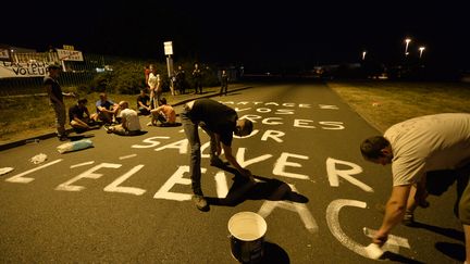 Des producteurs de lait &eacute;crivent un slogan ("partagez vos marges pour sauver l'&eacute;levage") sur la route&nbsp;d'acc&egrave;s &agrave; l'usine Lactalis en Mayenne, dans la nuit du jeudi 25 au vendredi 26 ao&ucirc;t 2016. (JEAN-FRANCOIS MONIER / AFP)