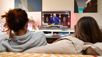 Des Français regardent une intervention&nbsp;du Premier ministre à la télévision, le 28 avril 2020, à Hede-Bazouges (Ille-et-Vilaine). (DAMIEN MEYER / AFP)