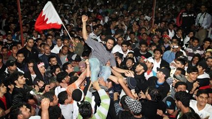 Un prisonnier libéré est porté par la foule des manifestants à Manara, capitale de Bahreïn, le 23 février 2011 (AFP)