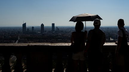 Des passants se protègent de la chaleur à Lyon (Rhône), le 20 août 2023. (NICOLAS LIPONNE / HANS LUCAS / AFP)