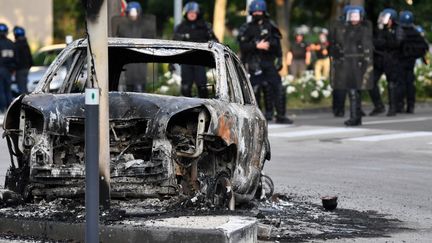 Des gendarmes patrouillent près d'une voiture brûlée, le 15 juin 2020 à Dijon (Côte-d'Or). Durant trois nuits, le quartier des Grésilles a été secoué par des violences après l'arrivée de dizaines de personnes d'origine tchétchène, venus venger l'agression d'un membre de leur communauté. (PHILIPPE DESMAZES / AFP)