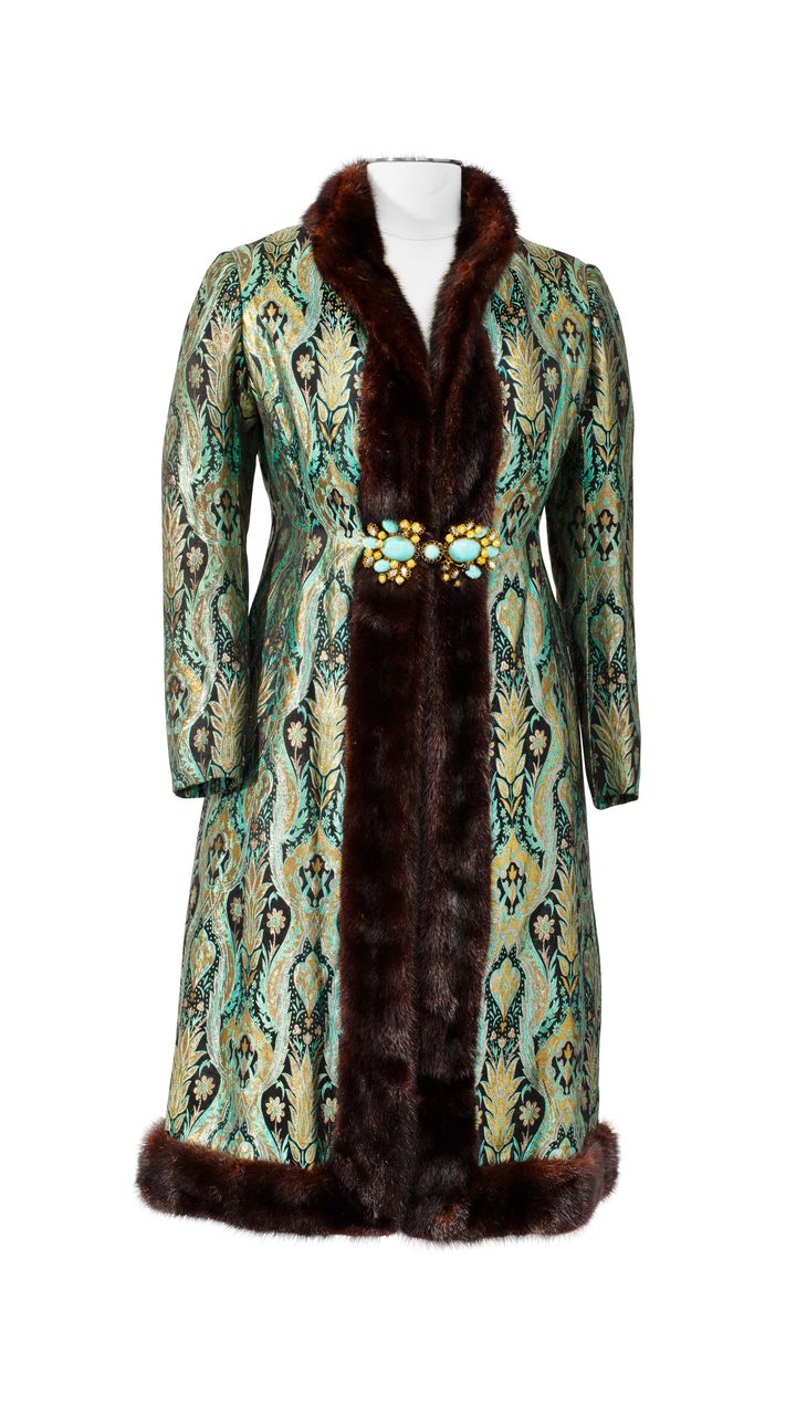 Nina Ricci par Gérard Pipart haute couture automne-hiver 1964-1965.&nbsp;Manteau ajusté en broché de soie turquoise bordé de fourrure noire et fermé par une large boucle bijou ornée de cabochons turquoise.&nbsp;Estimation : 5 000-7 000 €.&nbsp;Claudia Cardinale porte ce manteau en couverture du magazine italien Noi Donne du 9 décembre 1967. (SOTHEBY'S/ART DIGITAL STUDIO)