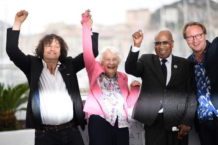 Andrew Mlangeni, bras levé, avec les réalisateurs du documentaire «L'Etat contre Mandela et les autres». (LOIC VENANCE / AFP)