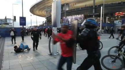 Un policier charge un supporter en marge de la finale de la Ligue des champions, le 28 mai 2022 au Stade de France. (MARYAM EL HAMOUCHI / AFP)