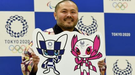 Ryo Taniguchi pose avec les deux mascottes de Tokyo-2020 qu'il a créées