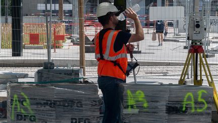 Un ouvrier du bâtiment travaille et se désaltère sur un chantier à Nantes (Loire-Atlantique), le 15 juin 2022.&nbsp; (ESTELLE RUIZ / HANS LUCAS / AFP)