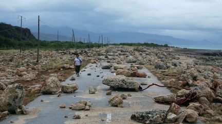 Une femme marche sur une route jonchée de pierres dans la baie de Guantanamo (Cuba), après le passage de l'ouragan Matthew, &nbsp;le 5 octobre 2016. (ALEXANDRE MENEGHINI / REUTERS)