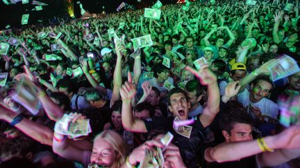 Des spectateurs essaient d'attraper de faux billets de banque, pendant un concert du groupe Phoenix, aux Eurock&eacute;ennes de Belfort, le 6 juillet 2013. (SEBASTIEN BOZON / AFP)