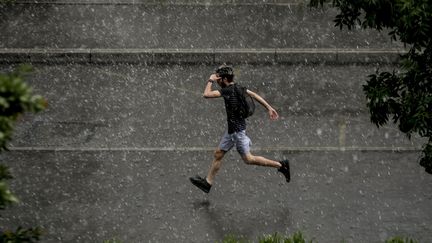 Un homme court sous une pluie d'orage, le 23 mai 2022, à Lyon. (MAXPPP)