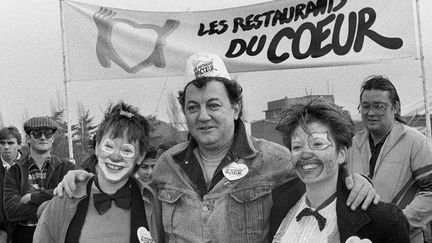 Le 21 décembre 1985, Coluche pose avec deux femmes déguisées en clown devant l'un des trois restaurants des Restos du coeur en région parisienne
 (MICHEL GANGNE / AFP)